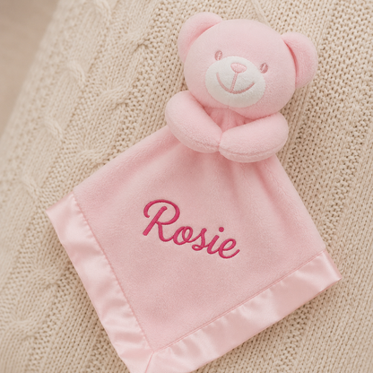 Pink teddy bear security blanket with 'Rosie' embroidered on a textured beige background
