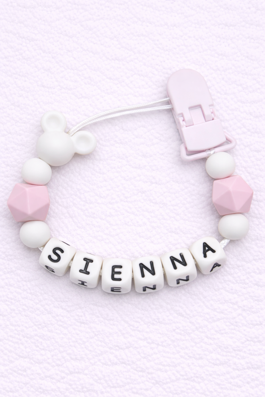 Baby dummy clip with letter beads spelling 'SIENNA' on a light pink background