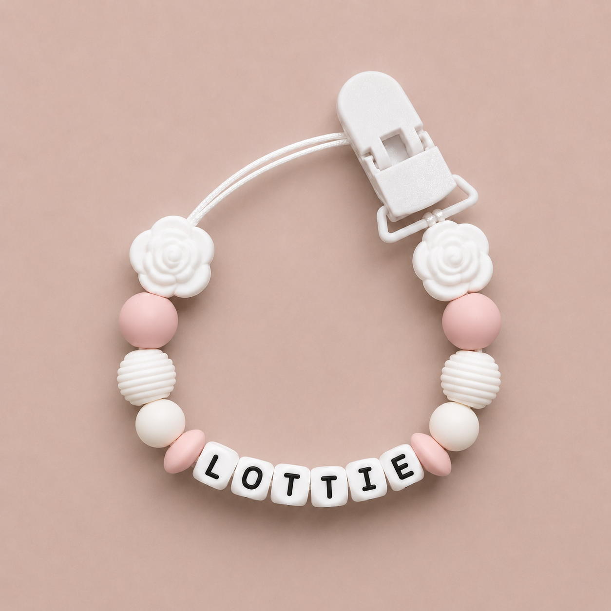 Baby dummy clip with 'LOTTIE' on a beige background