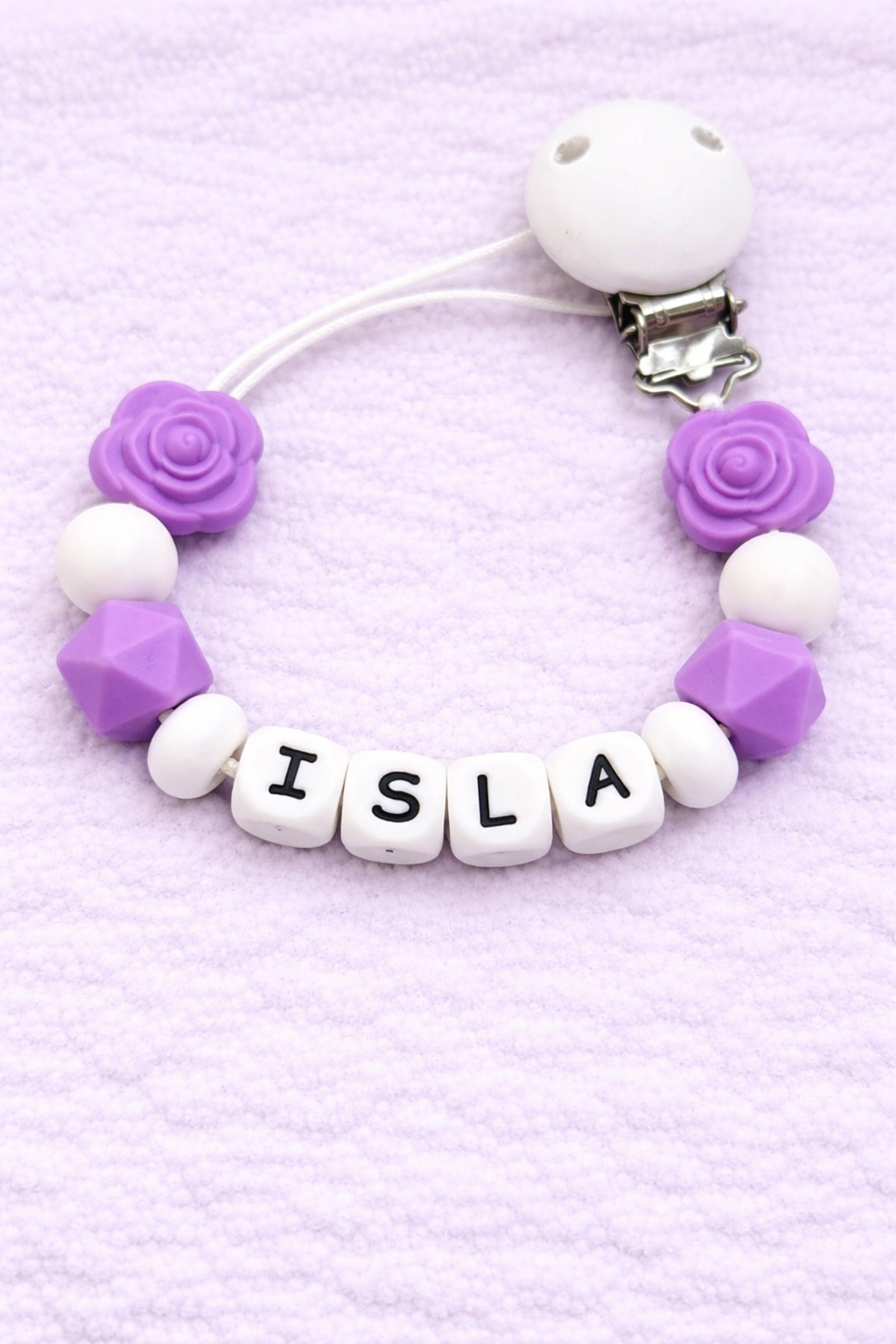 Pacifier clip with 'Isla' on a purple background