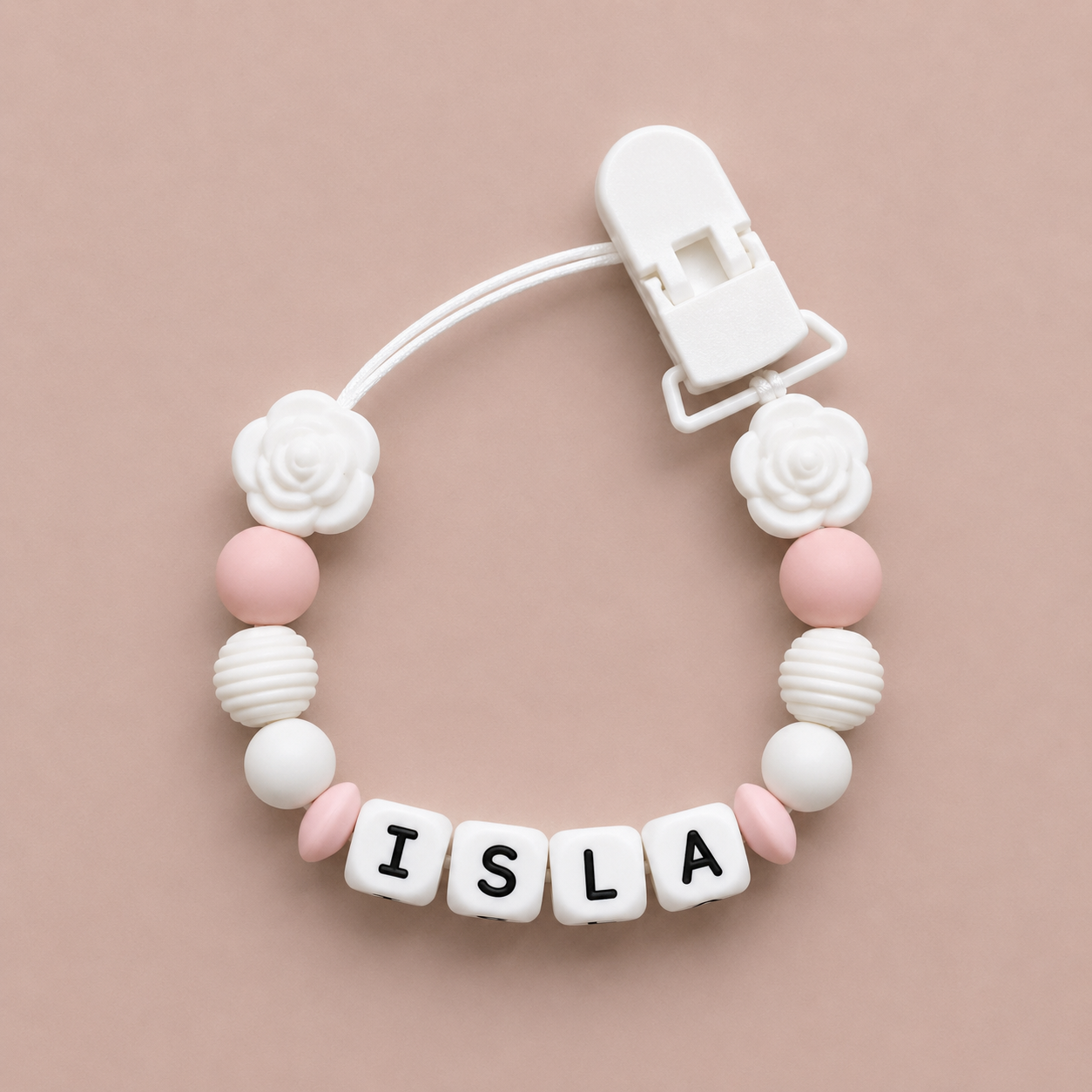 Baby dummy clip with 'ISLA' beads on a beige background