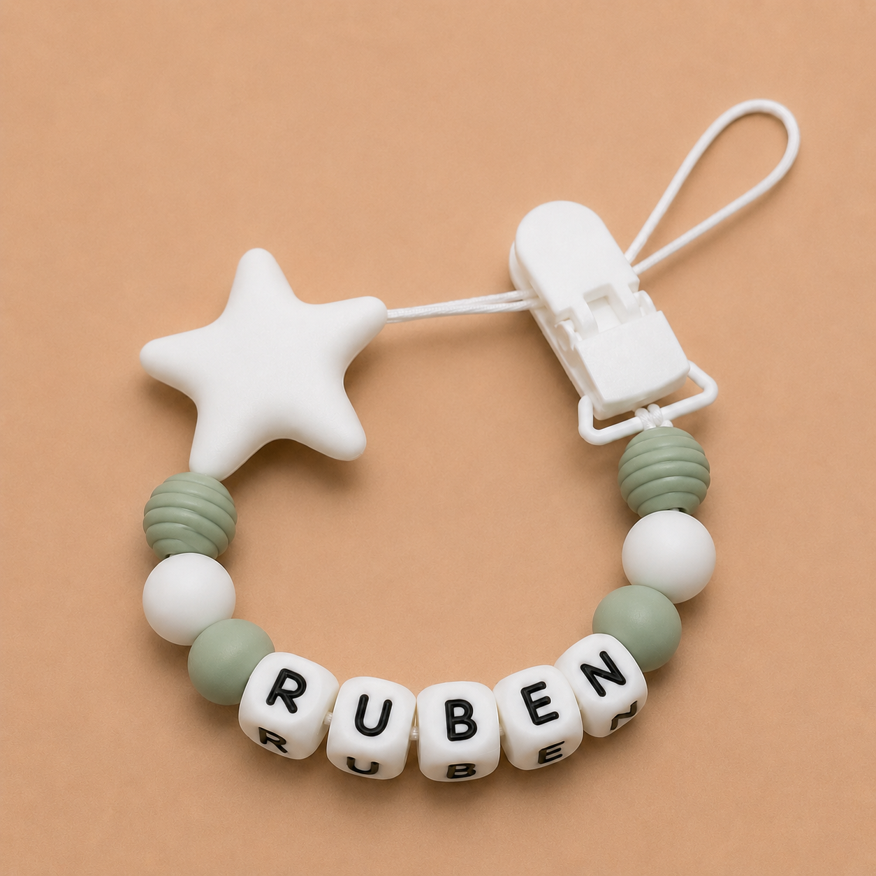 dummy clip with star-shaped chewable and letter beads spelling 'RUBEN' on a beige background