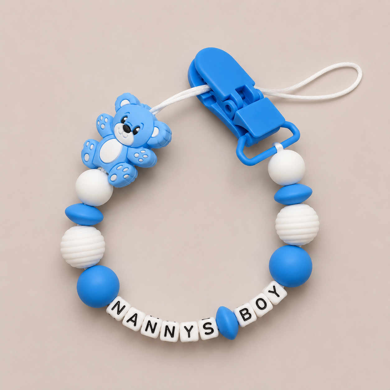 Blue and white baby dummy clip with a clip on a beige background