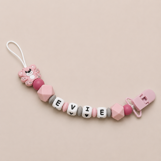 Pink and gray dummy clip with 'EVIE' beads on a beige background