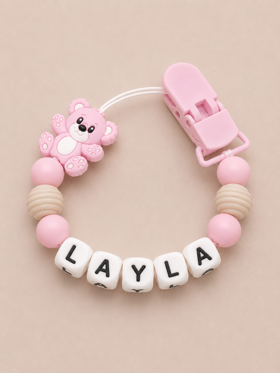 Pink and beige dummy clip with 'LAYLA' on a beige background