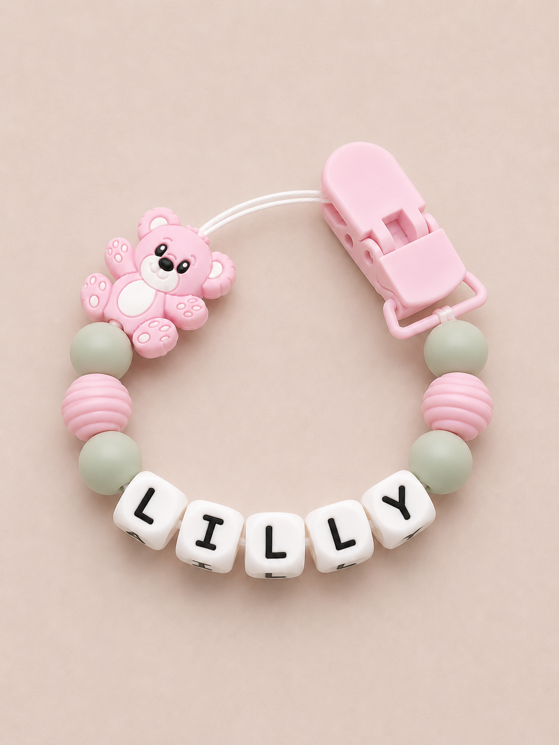 Baby dummy clip with name 'LILLY' on a beige background