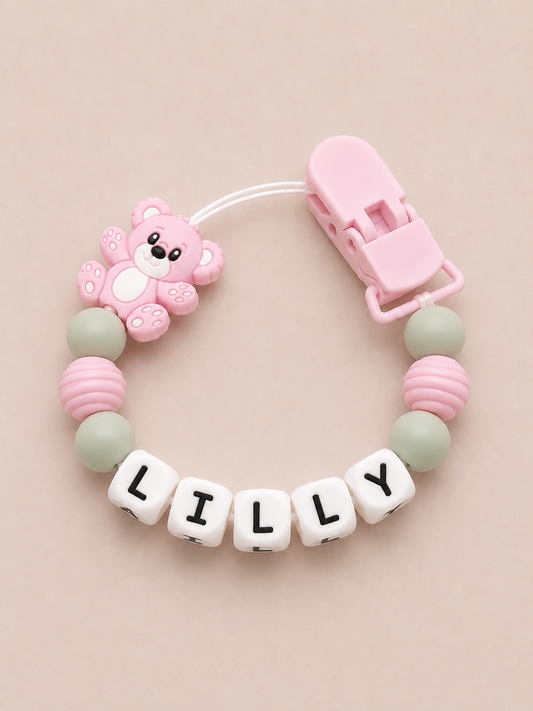 Baby dummy clip with name 'LILLY' on a beige background