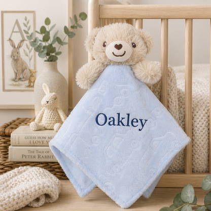 Baby comfort blanket with teddy bear and name 'Oakley' in a nursery setting