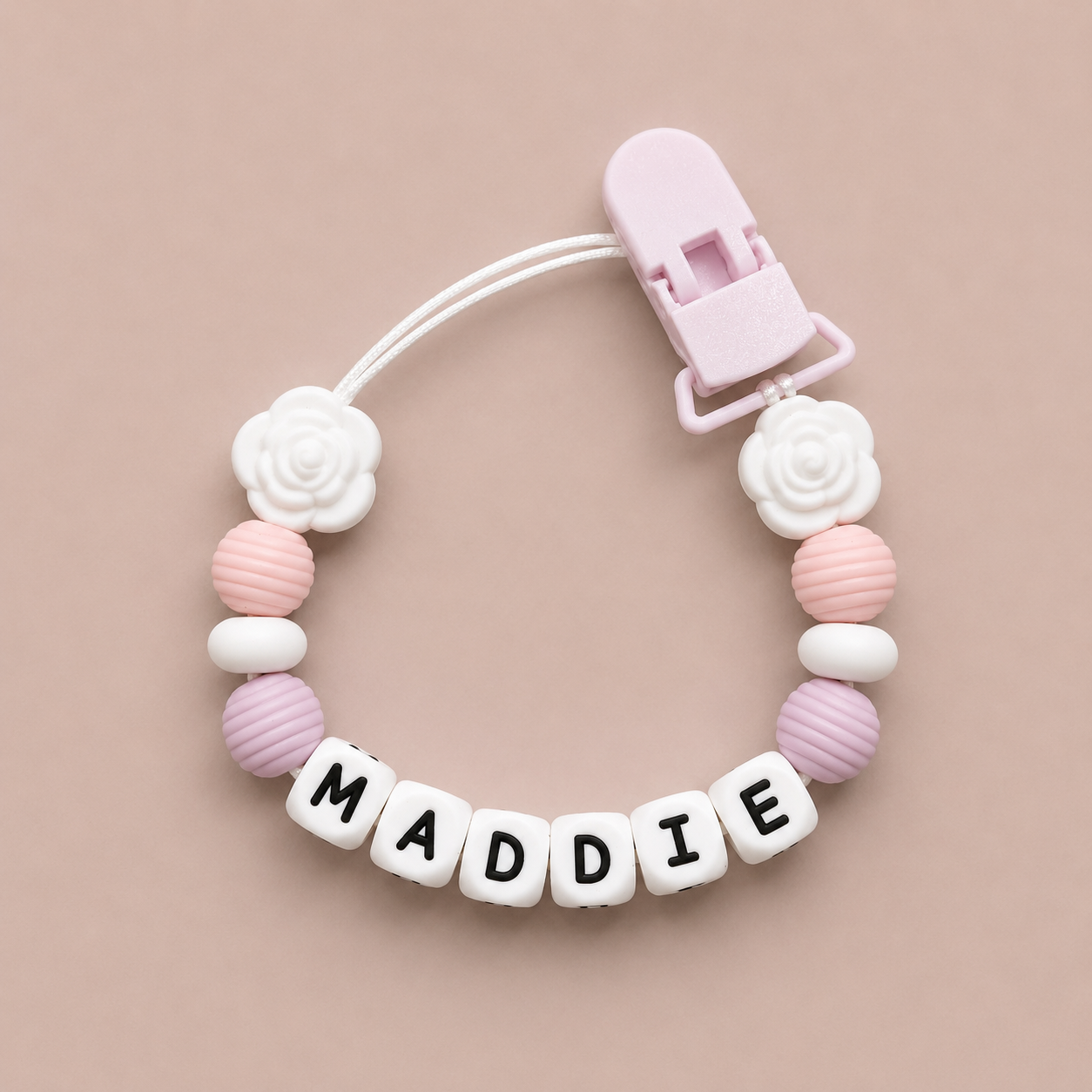 Baby dummy clip with 'MADDIE' on a pink background