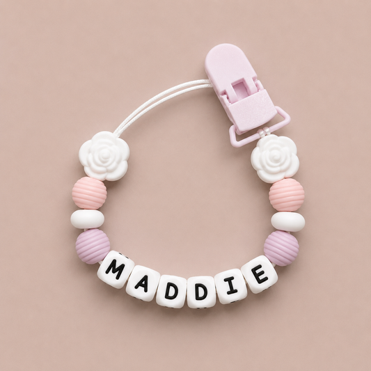 Baby dummy clip with 'MADDIE' on a pink background