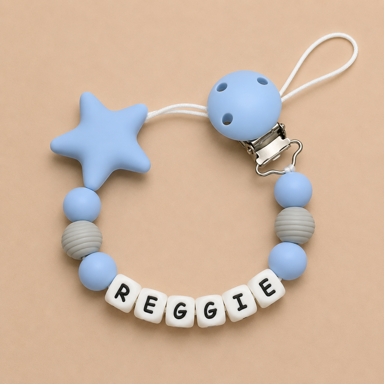 Baby dummy clip with star and round beads on a beige background