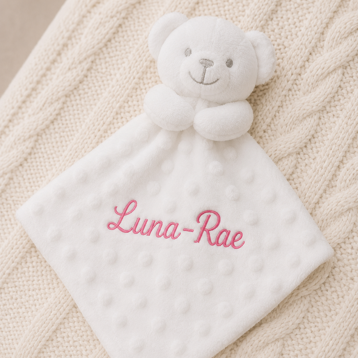 White teddy bear security blanket with 'Luna-Rae' embroidered on a textured beige surface
