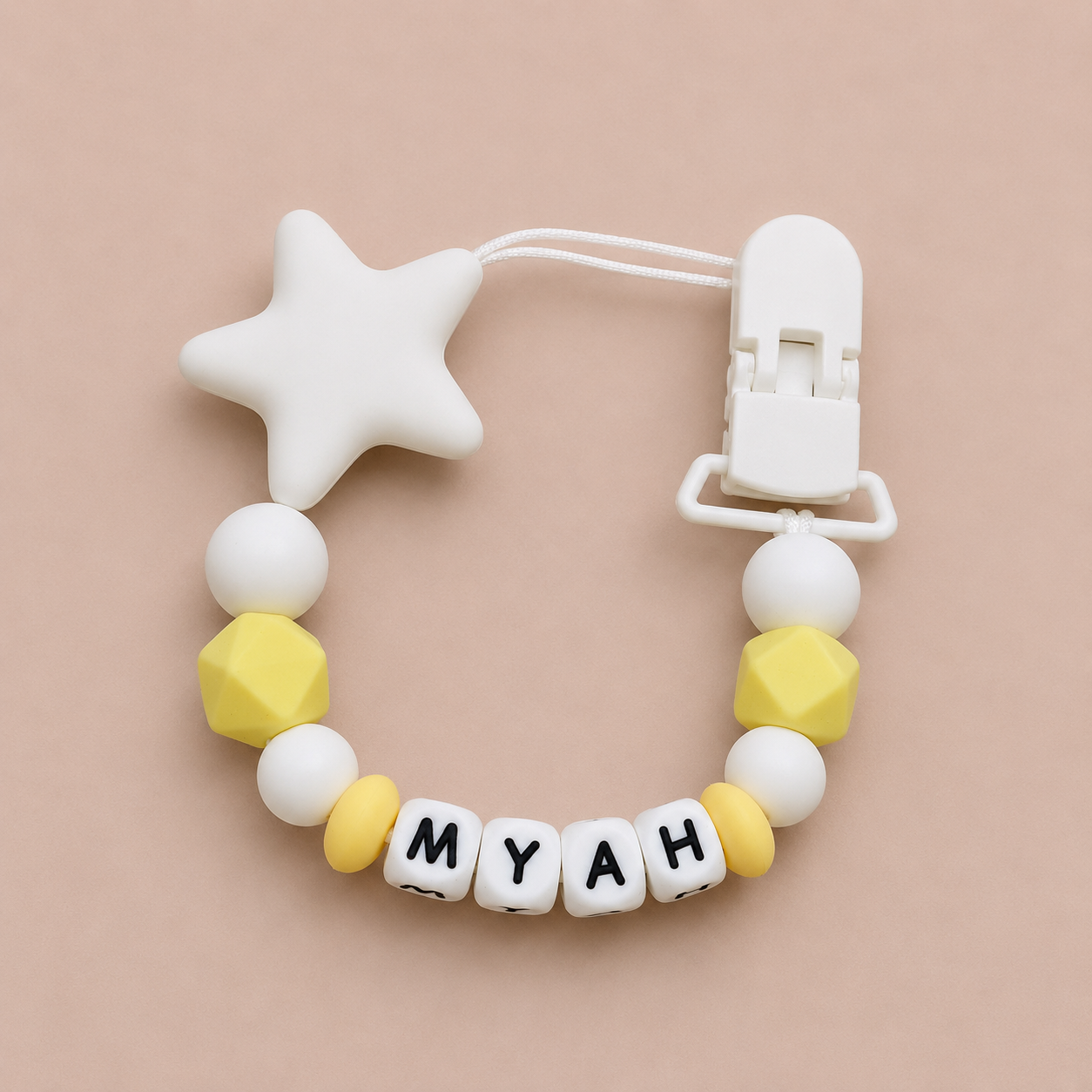 dummy clip with star-shaped clip and 'MYAH' beads on a beige background