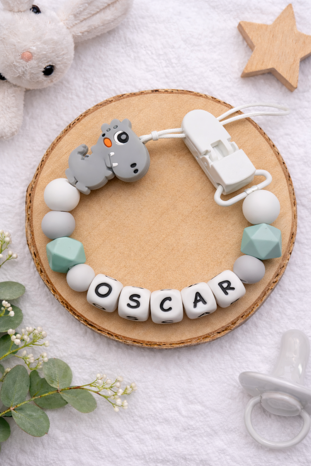 Green, grey and white personalised dummy clip featuring a dinosaur design for babies.