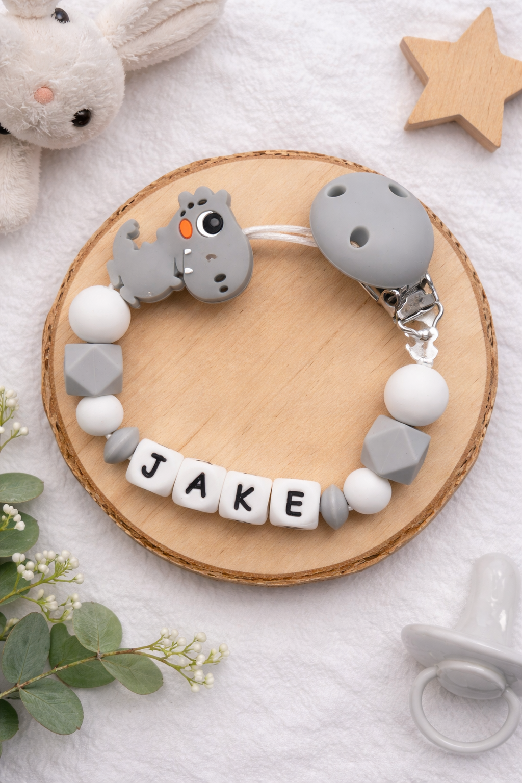 Grey personalised dummy clip featuring a dinosaur design for babies.