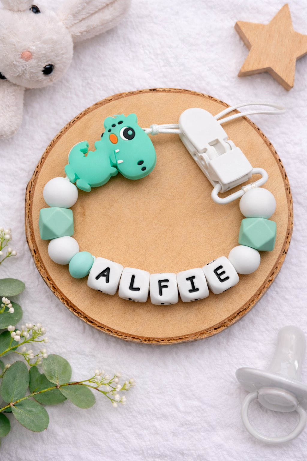 Mint green personalised dummy clip featuring a dinosaur design for babies.