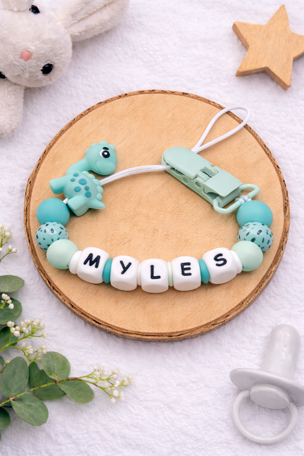 Mint green personalised dummy clip featuring a dinosaur design for babies.