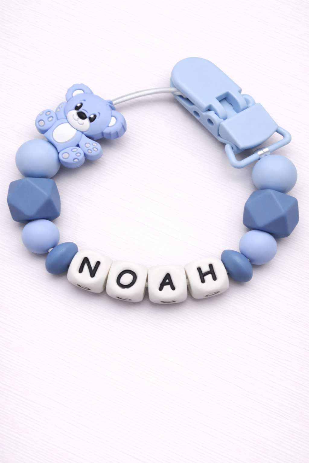 Blue baby teether with 'NOAH' beads on a white background