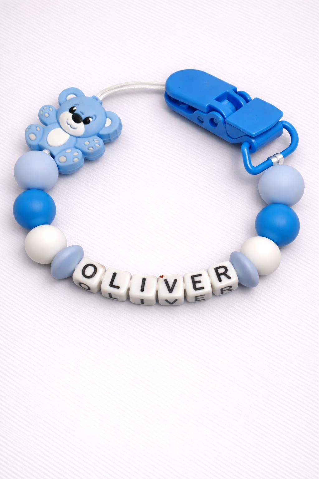 Blue and white pacifier clip with 'OLIVER' beads on a white background