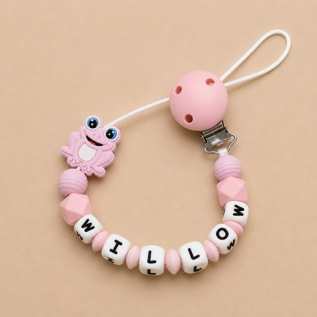 Pink baby dummy clip with letter beads spelling 'WILLOW' on a beige background
