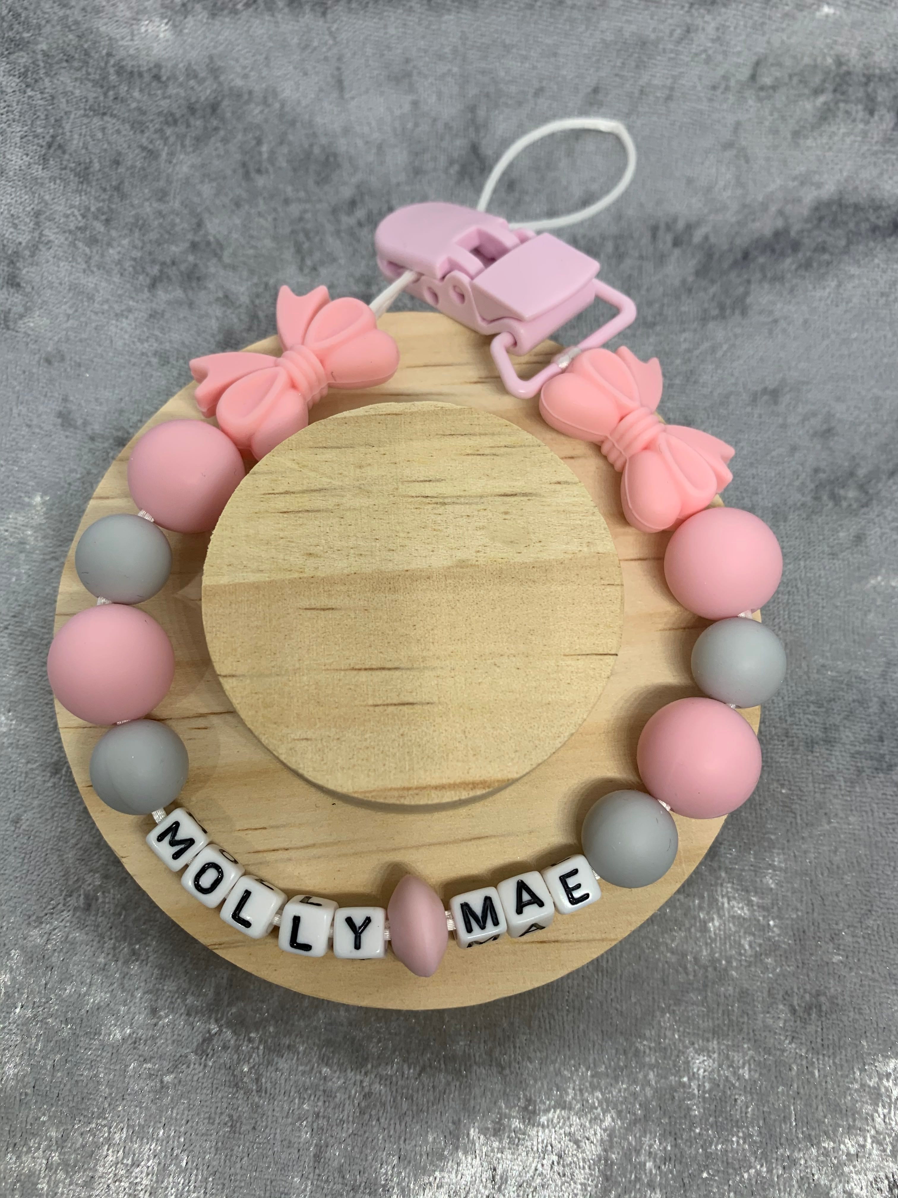 Pacifier Clip with colorful beads and name 'Molly Mae' on a gray background