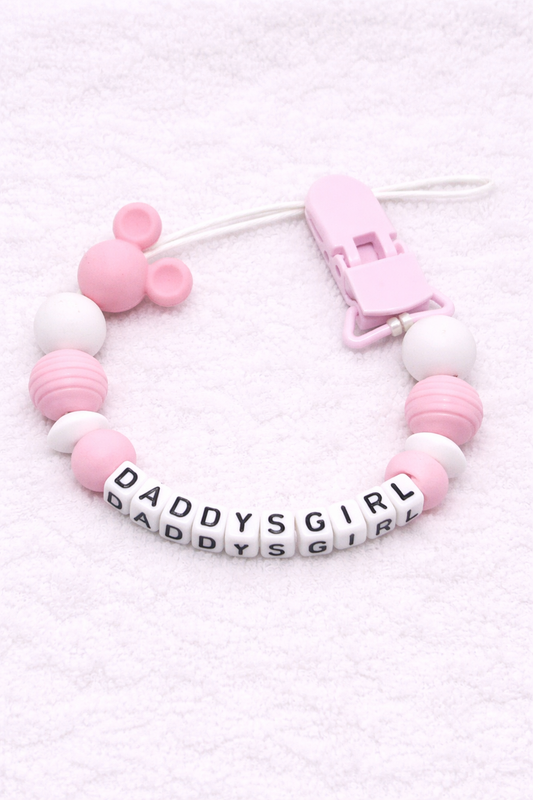 Pink and white teething dummy clip with 'DADDYS GIRL' beads on a light pink background