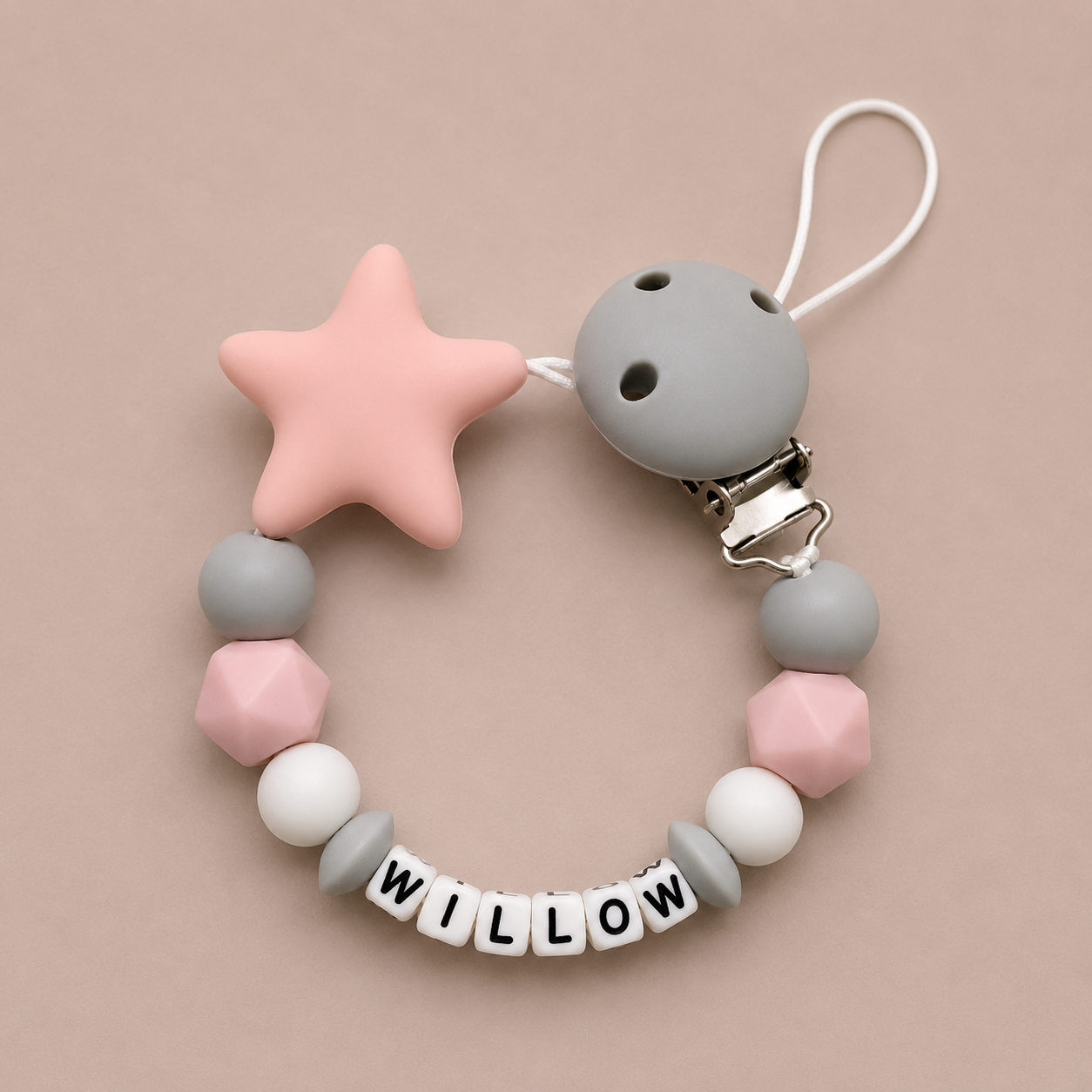 Baby dummy clip with star and round beads on a beige background