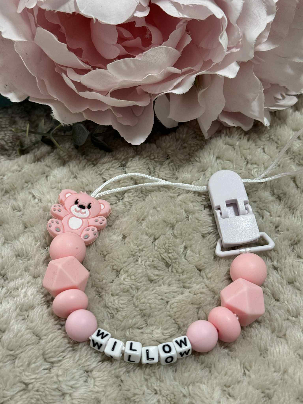 Pink teddybear dummy clip on a beige textured surface with flowers at the top. Personalised with the name 'Willow'. Change of name is available in the personalisation box. MAM Adapters are available too.