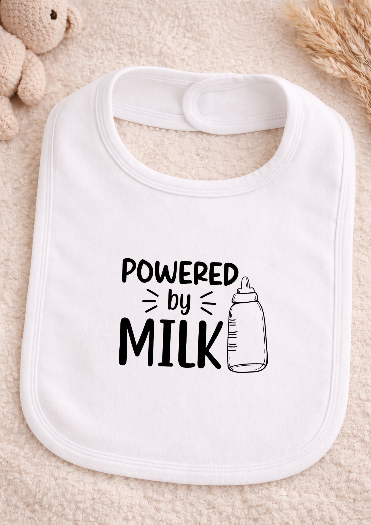 White bib with 'Powered by Milk' text on a beige surface