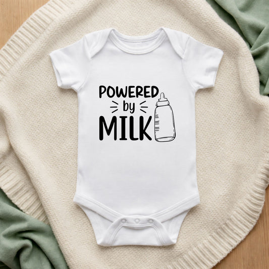 White baby onesie with 'Powered by Milk' text on a textured surface