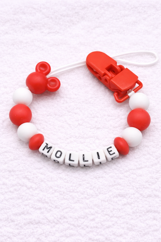 Red and white pacifier clip with 'MOLLIE' on a textured white background