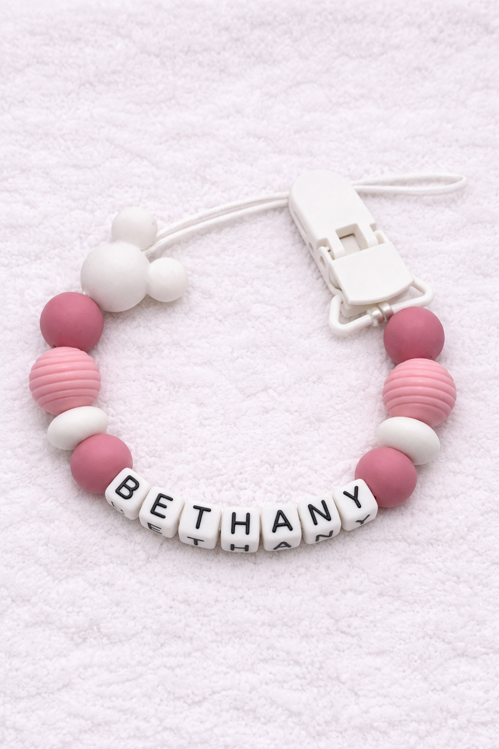 Dummy Clip with pink and white beads and a name tag on a white background
