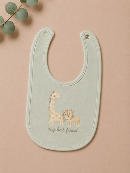 Light green baby bib with embroidered giraffe and lion design on a beige background