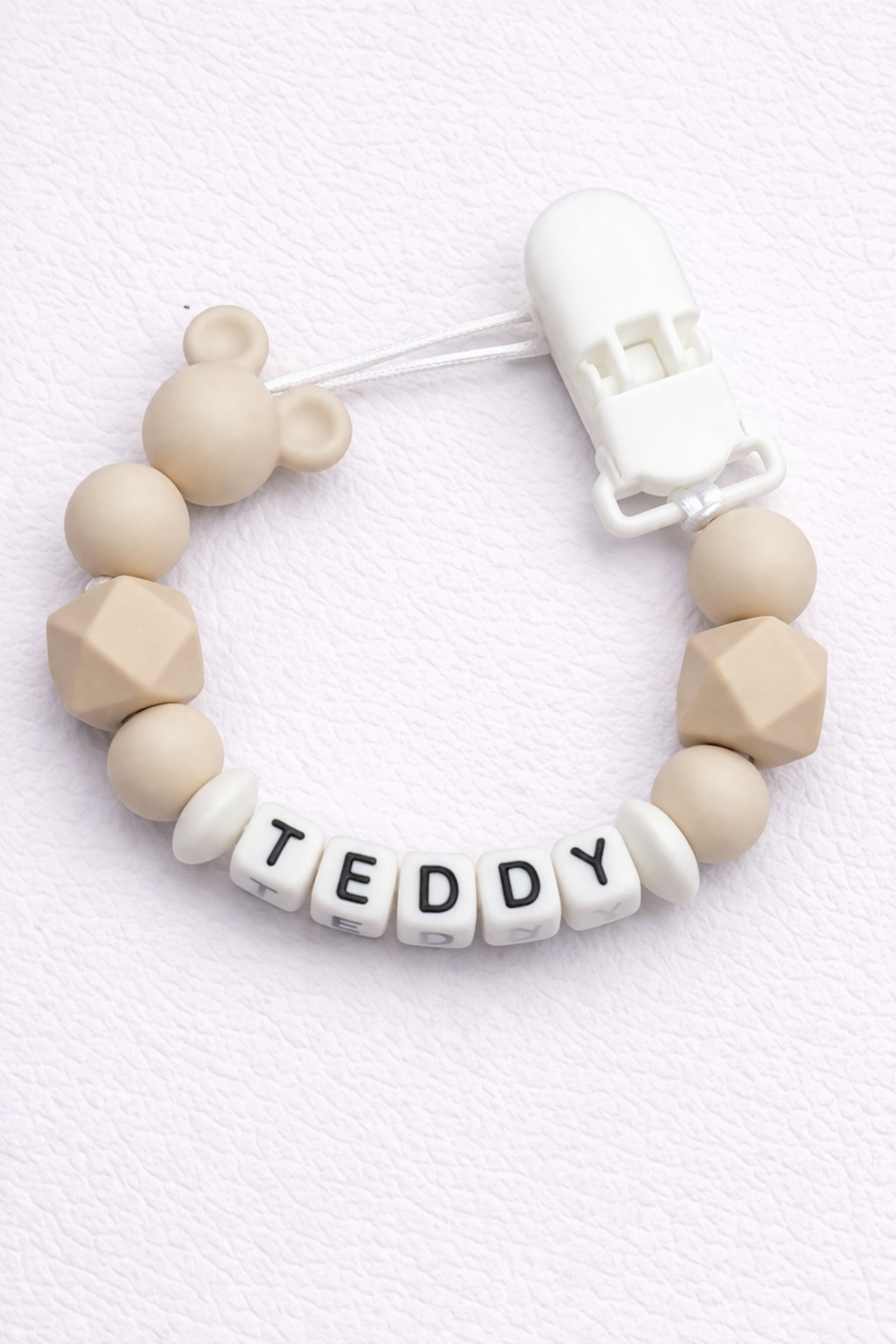 dummy clip with silicone beads and 'TEDDY' letter beads on a light background