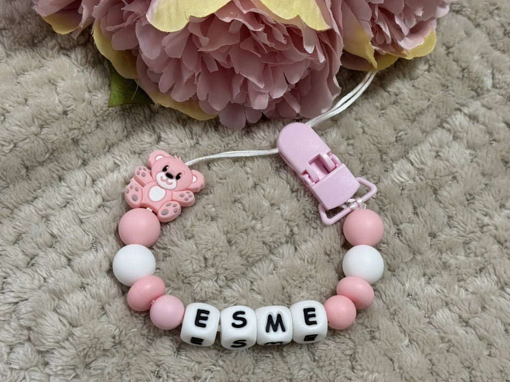 Pink teddybear dummy clip on a beige textured surface with flowers at the top. Personalised with the name 'Esme'. Change of name is available in the personalisation box. MAM Adapters are available too.