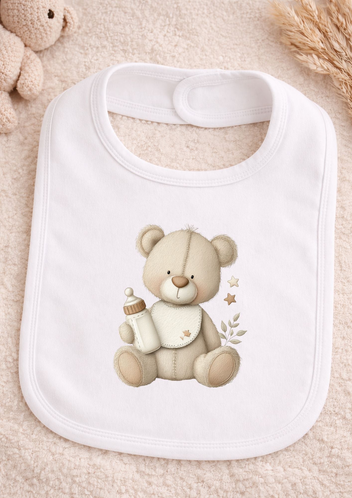 White bib with a teddy bear design holding a bottle on a beige background