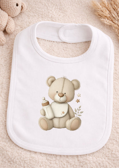 White bib with a teddy bear design holding a bottle on a beige background