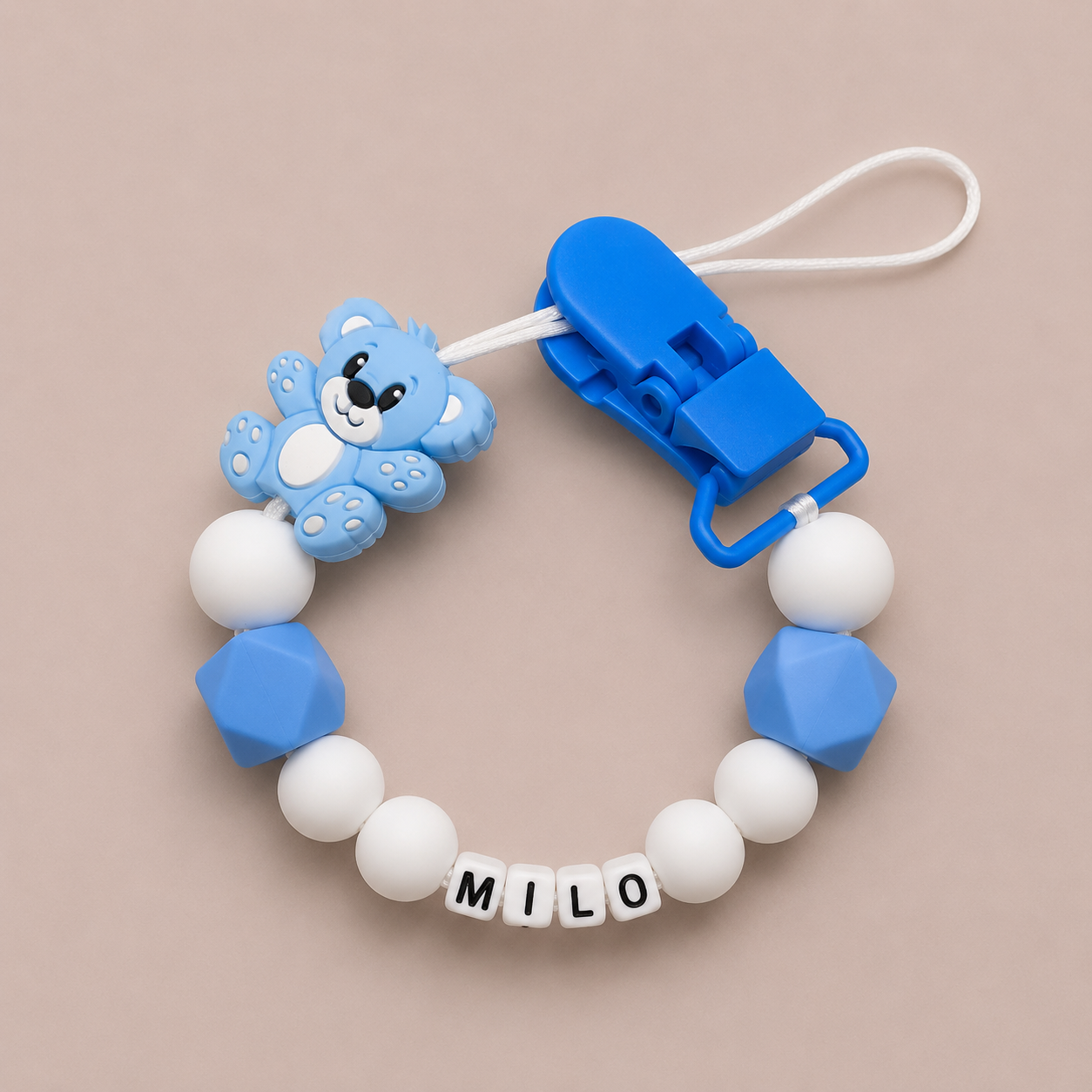 Blue and white dummy clip with a bear design on a beige background