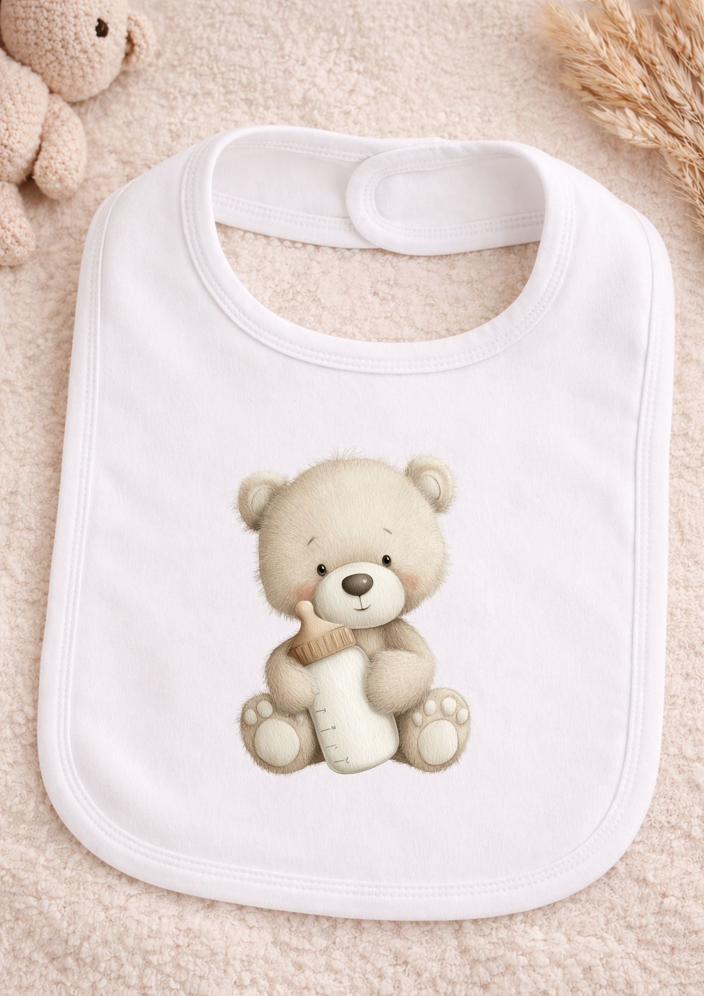 White baby bib with teddy bear design on a soft beige background