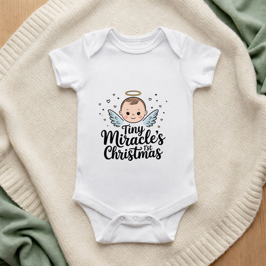 White baby onesie with an angel design and text on a textured surface