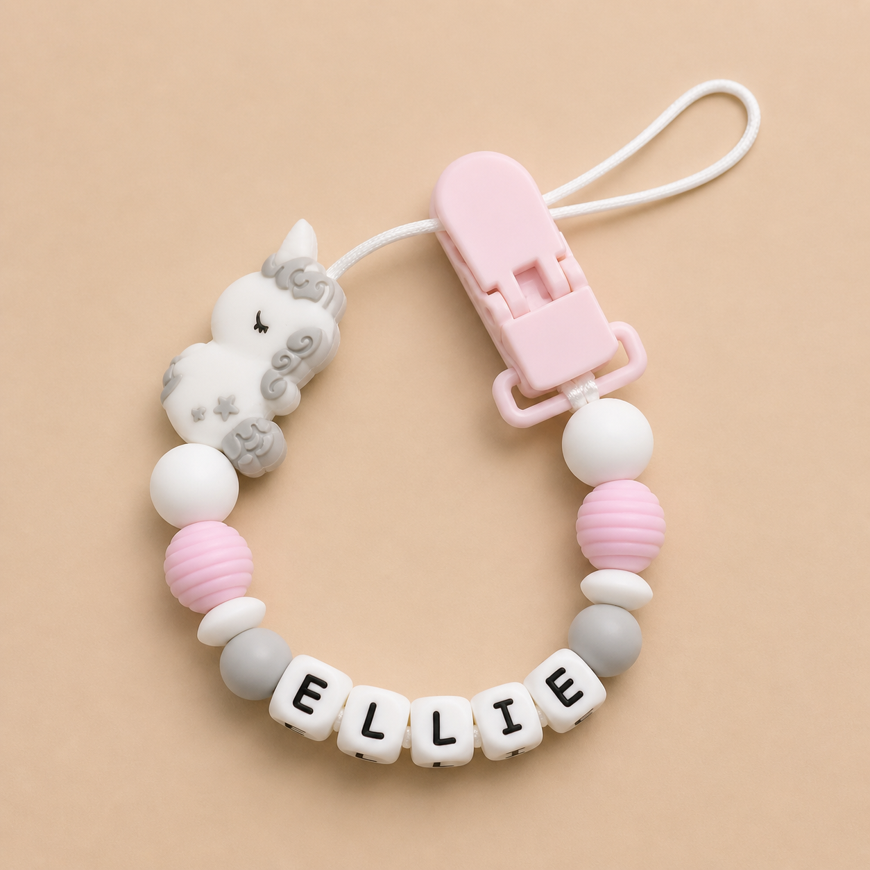 Baby dummy clip with name 'ELLIE' on a beige background