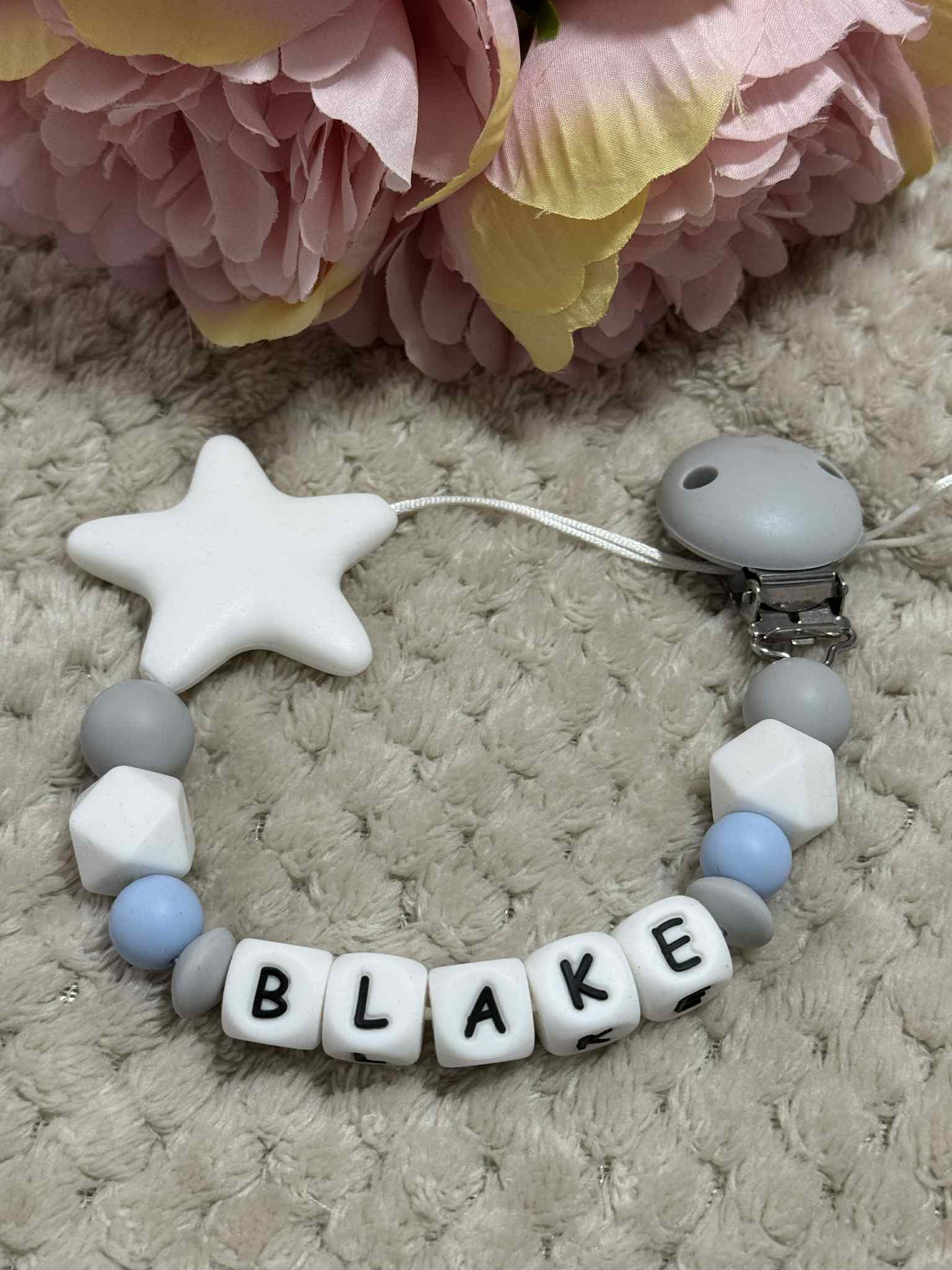 A dummy clip in Grey, blue and white colors, personalized with any name 