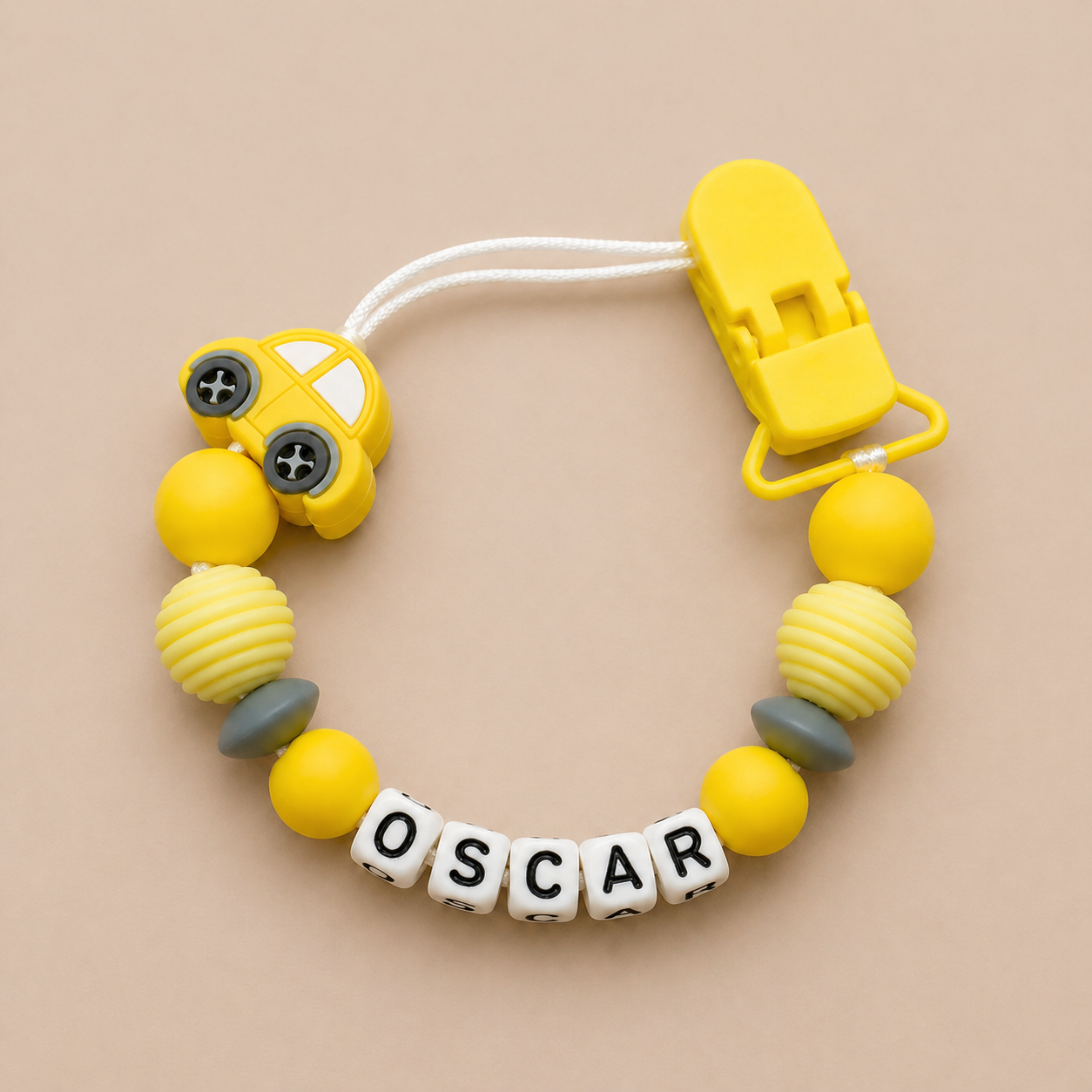 Yellow and gray dummy clip with 'OSCAR' on a beige background