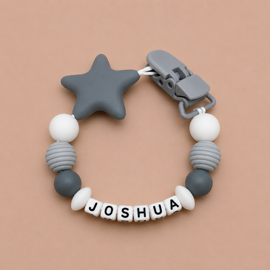dummy clip with star-shaped clip and 'JOSHUA' name on a beige background