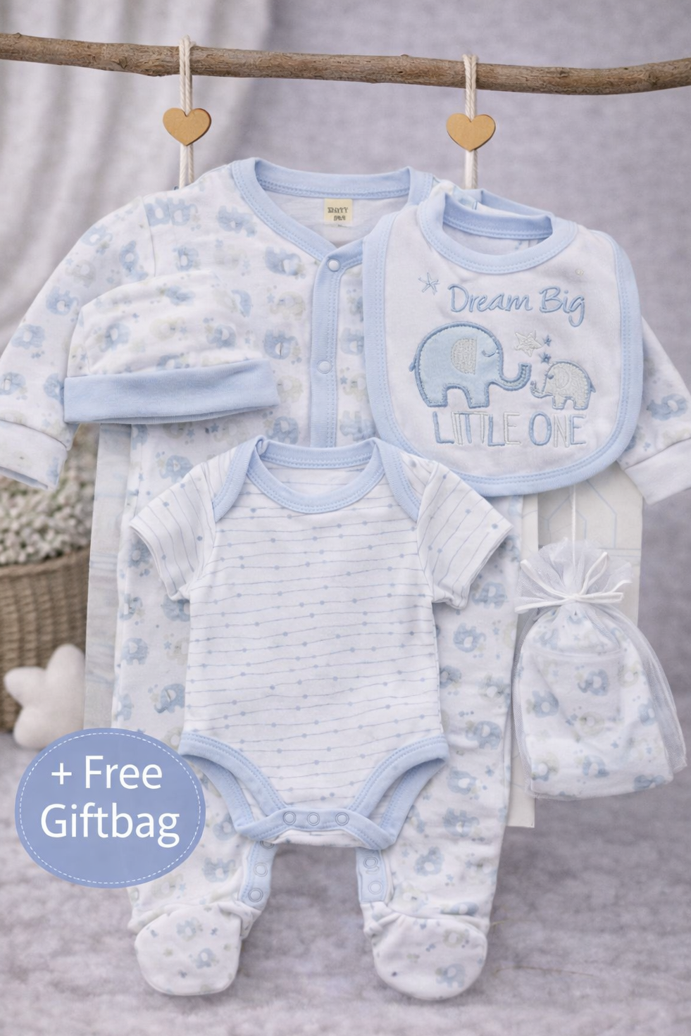 Baby boy gift set with clothes and accessories on a wooden stick against a neutral background.
