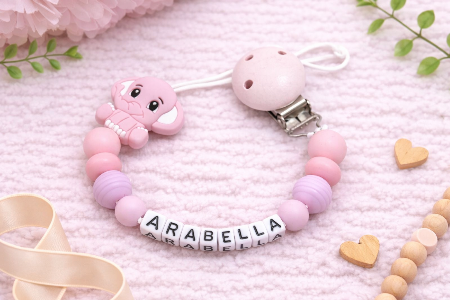 Pink and purple pacifier clip with 'ARABELLA' on a soft pink background