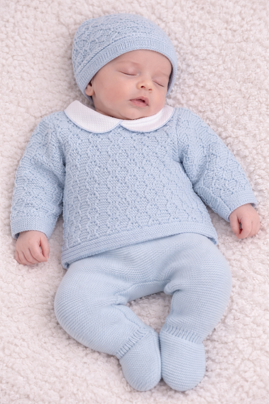Newborn baby in a light blue knitted outfit lying on a soft surface