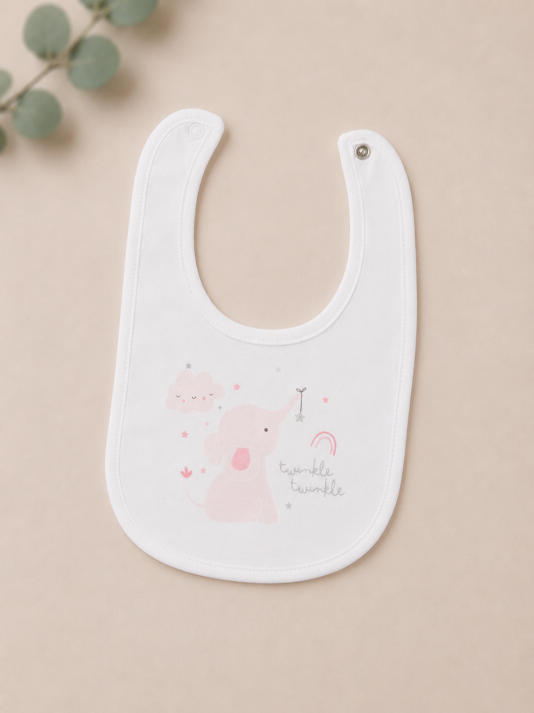 White baby bib with pink graphics on a beige background