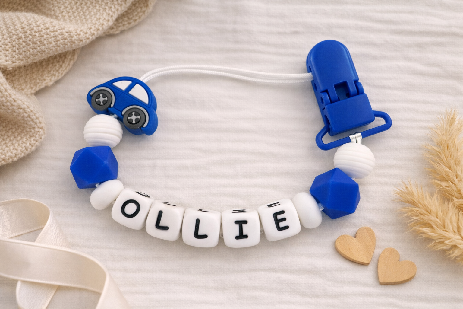 Silicone teether with 'OLLIE' letters on a soft surface with decorative elements.