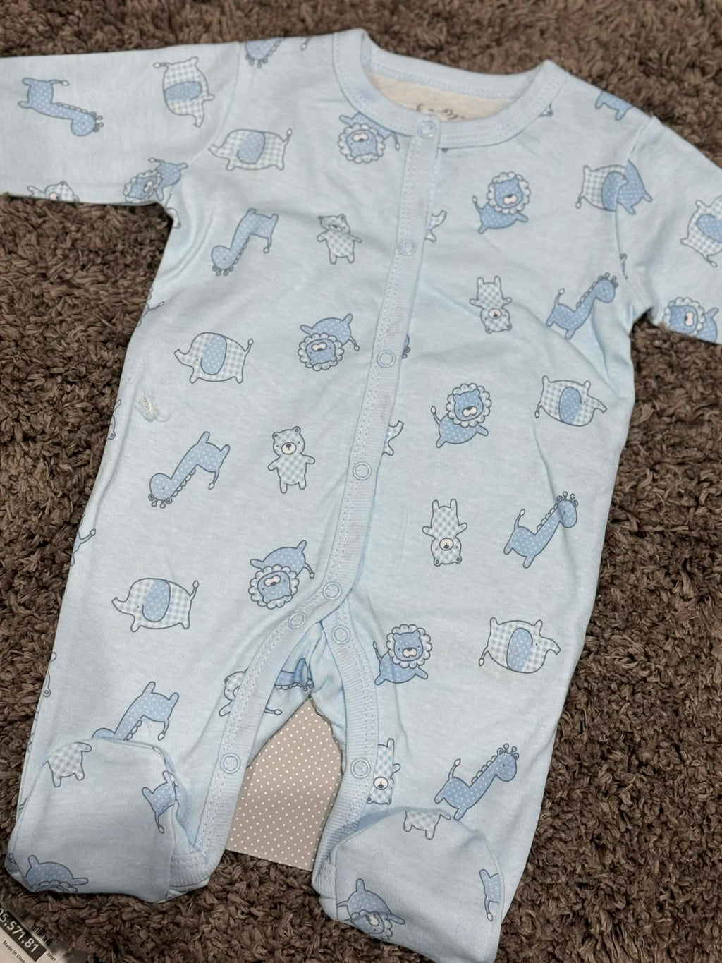 Baby onesie with blue animal patterns on a brown carpet